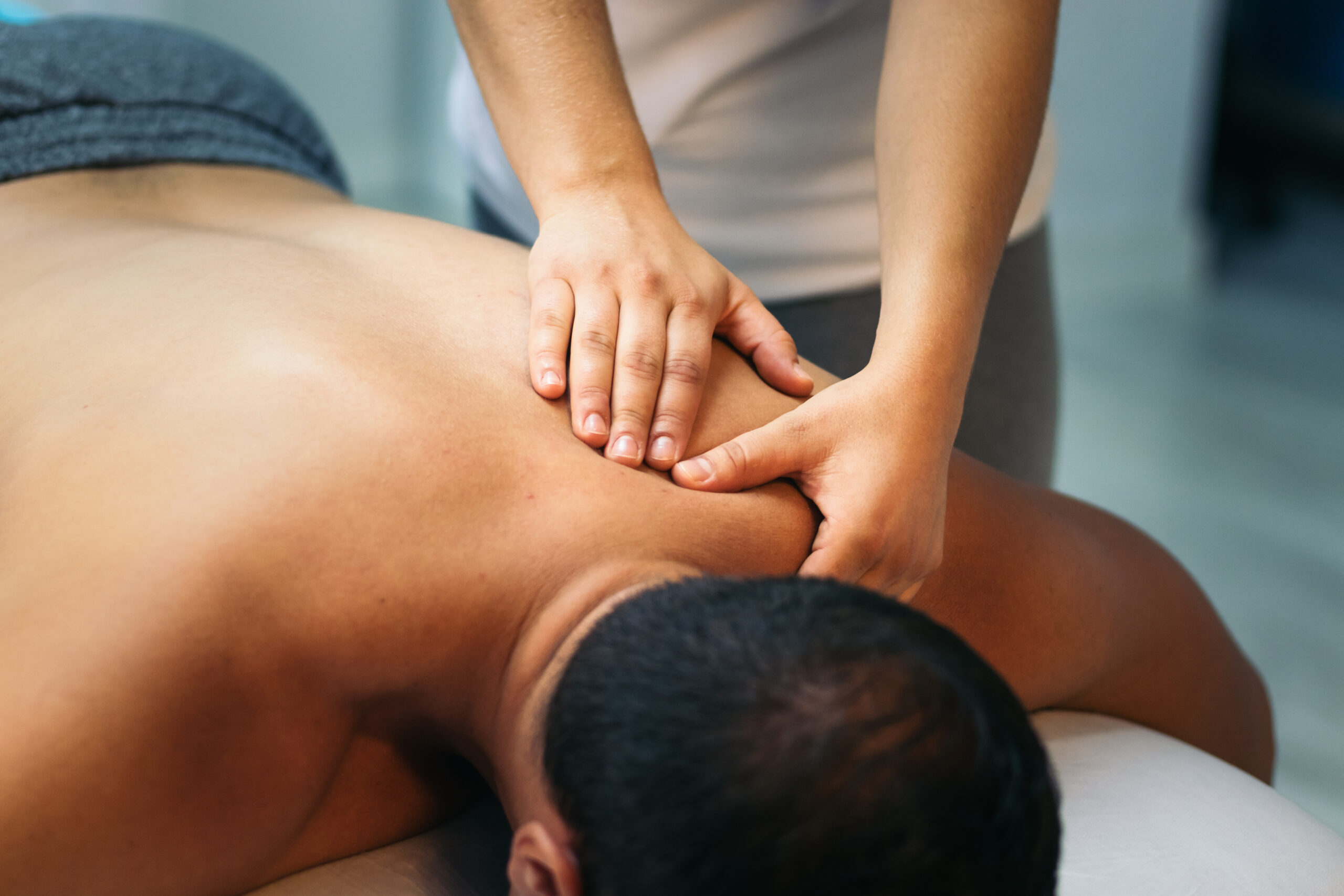 young woman treating a male patient. back massage physiotherapy. close-up